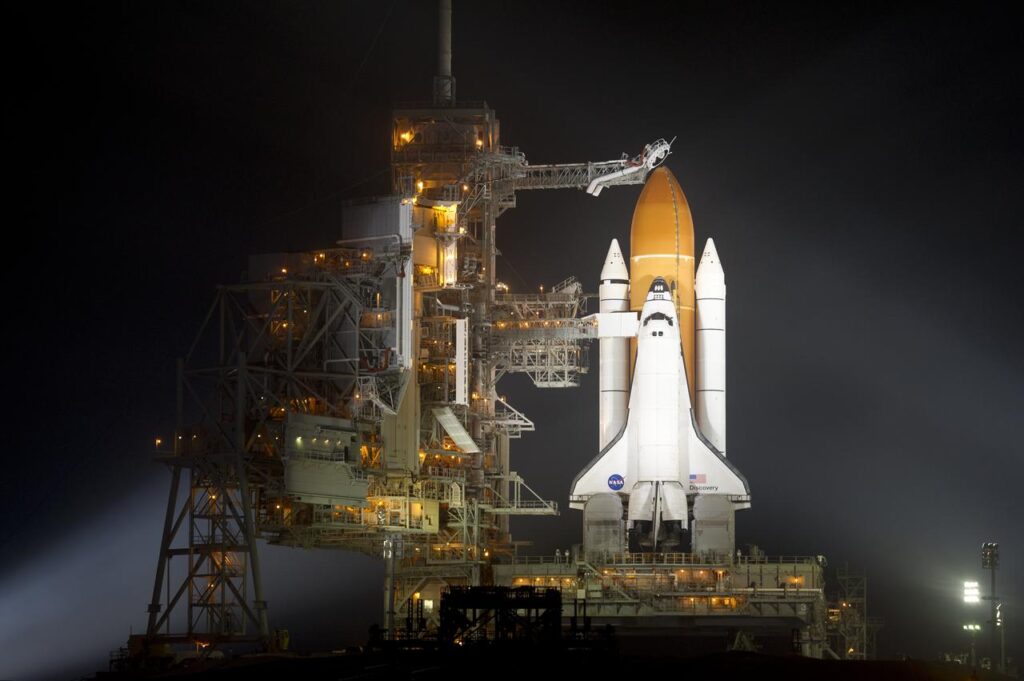A photograph of the NASA Space Shuttle on the launch pad at night